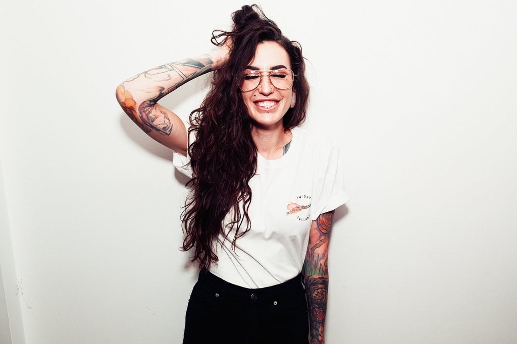 Twiggy Tallant smiling wearing a white shirt with her logo on it.