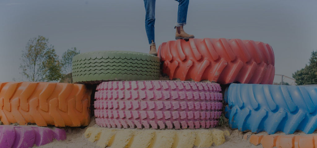 Multicoloured truck tires laid flat with Twiggy Tallant's legs and boot showing as she stands on top of them